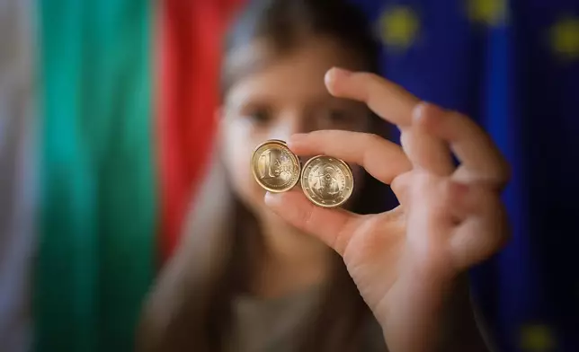 A girl poses as she holds new euro coins with Bulgarian symbols in Sofia, Tuesday Dec. 30, 2025. (AP Photo/Valentina Petrova)