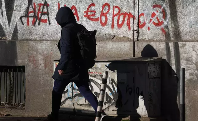 A woman passes by a graffiti reading "No to the euro" altered to "Yes to the euro" in Sofia, Monday, Dec. 29, 2025. (AP Photo/Valentina Petrova)