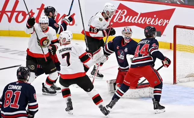 Ottawa Senators' Brady Tkachuk (7) and Dylan Cozens (24) celebrate after a tying goal by teammate Jake Sanderson (not shown) in front of Winnipeg Jets goaltender Connor Hellebuyck, second from right, during the third period of an NHL hockey game in Winnipeg, Manitoba, Monday, Dec. 15, 2025. (Fred Greenslade/The Canadian Press via AP)