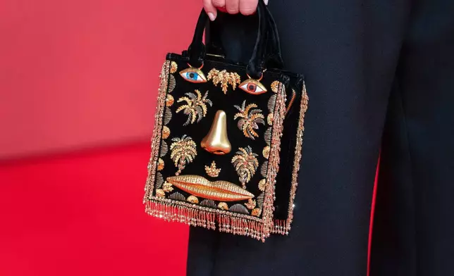 An actress holds a Schiaparelli purse while posing for a photo on the red carpet during 22nd Marrakech Film Festival, in Morocco, Tuesday, Dec. 2, 2025. (AP Photo/Mosa'ab Elshamy)