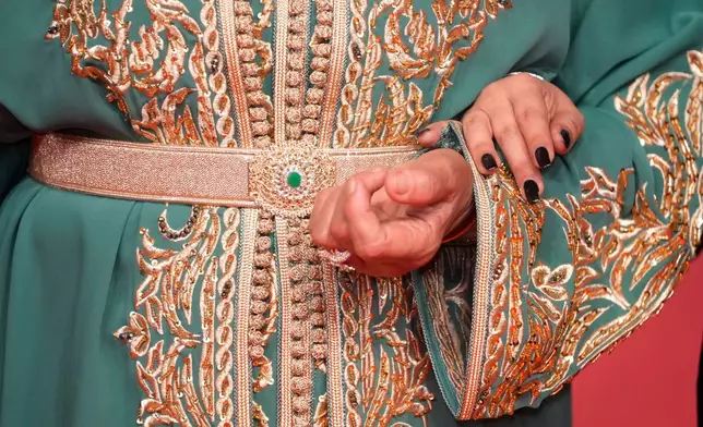 Moroccan actress Fatima Hernadi, also known as Raouia, holds her daughter, while wearing a caftan, as they poses for a photo on the red carpet during the opening ceremony of the 22nd Marrakech Film Festival, in Morocco, Friday, Nov. 28, 2025. (AP Photo/Mosa'ab Elshamy)