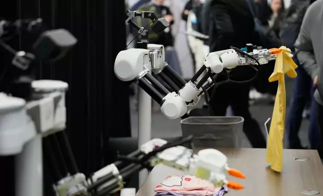 Robots, made by Weave Robotics, fold clothes inside the exhibition room at the Humanoids Summit, Thursday, Dec. 11, 2025, in Mountain View, Calif. (AP Photo/Godofredo A. Vásquez)