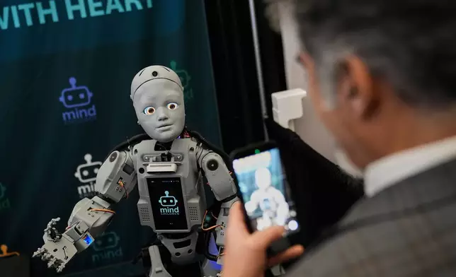 A man records a humanoid robot inside the exhibition room at the Humanoids Summit, Thursday, Dec. 11, 2025, in Mountain View, Calif. (AP Photo/Godofredo A. Vásquez)