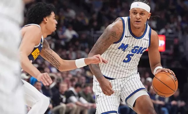 Orlando Magic forward Paolo Banchero, right, drives past Denver Nuggets guard Julian Strawther in the first half of an NBA basketball game, Thursday, Dec. 18, 2025, in Denver. (AP Photo/David Zalubowski)