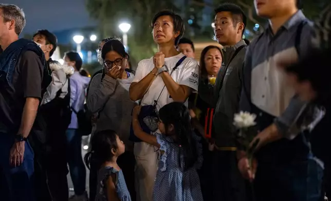 People pray after offering flowers for the victims near the site of a deadly fire at Wang Fuk Court, a residential estate in the Tai Po district of Hong Kong's New Territories on Tuesday, Dec 2, 2025. (AP Photo/Chan Long Hei)