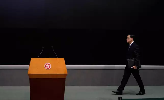 Hong Kong Chief Executive John Lee walks to a press conference with a darken screen in the aftermath of a deadly fire in Hong Kong on Tuesday, Dec. 2, 2025. (AP Photo/Ng Han Guan)