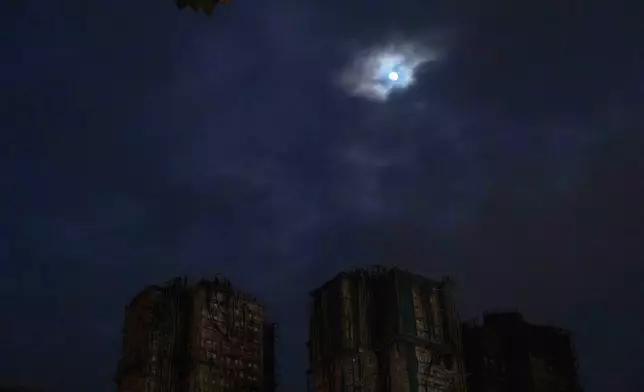 The moon rises over the site of a deadly fire at Wang Fuk Court, a residential estate in the Tai Po district of Hong Kong's New Territories, on Tuesday, Dec. 2, 2025. (AP Photo/Ng Han Guan)