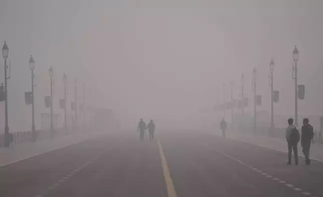 People walk in a smog-covered morning in New Delhi, India, Monday, Dec. 15, 2025. (AP Photo/Piyush Nagpal)