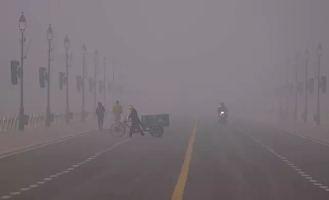 A man pushes a cycle cart in a smog-covered morning in New Delhi, India, Monday, Dec. 15, 2025. (AP Photo/Piyush Nagpal)