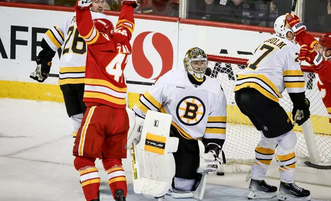 Boston Bruins goalie Jeremy Swayman, center, reacts as Calgary Flames' Connor Zary, front left, celebrates after his team's winning goal during overtime NHL hockey game action in Calgary, Alberta, Monday, Dec. 29, 2025. (Jeff McIntosh/The Canadian Press via AP)
