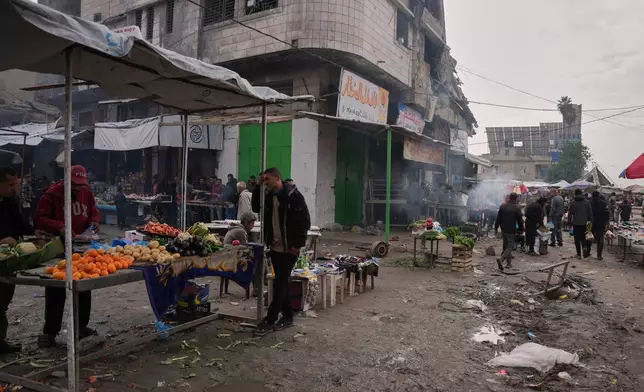 Palestinians walk along street market where fruits and vegetables are displayed for sale in Gaza City, Friday, Dec. 19, 2025. (AP Photo/Abdel Kareem Hana)