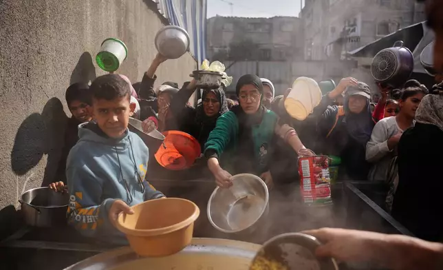 FILE - Palestinian women struggle to receive donated food at a community kitchen in Nuseirat, central Gaza Strip, Wednesday, Dec. 17, 2025. (AP Photo/Abdel Kareem Hana, File)