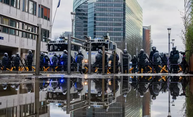 Police stand behind a barrier as European farmers block a road with their tractors during a demonstration outside the EU Summit in Brussels, Thursday, Dec. 18, 2025. (AP Photo/Marius Burgelman)