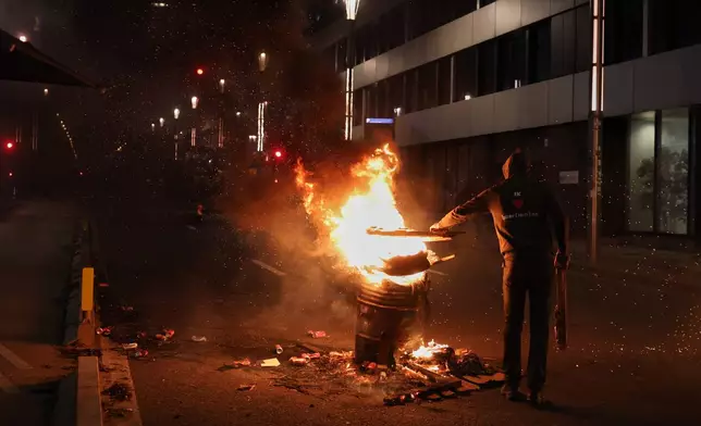 A farmer puts wood in a fire during a demonstration outside the EU Summit in Brussels, Thursday, Dec. 18, 2025. (AP Photo/Omar Havana)