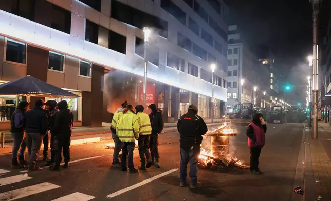Protestors and farmers stand next to a wood fire during a demonstration outside the EU Summit in Brussels, Thursday, Dec. 18, 2025. (AP Photo/Omar Havana)
