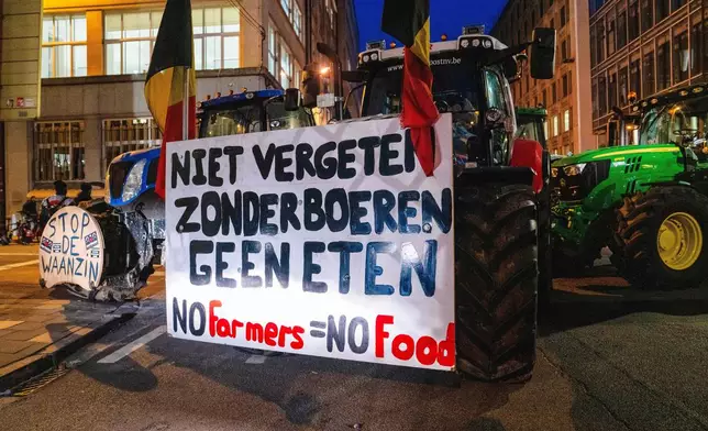 A farmer drives a tractor with a sign that reads in Dutch 'Don't forget, without farmers there's no food' during a demonstration outside a gathering of European leaders at the EU Summit in Brussels, Thursday, Dec. 18, 2025. (AP Photo/Marius Burgelman)