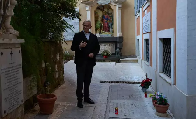 Mons. Peter Klasvogt, the rector of the Teutonic College poses for a photo next to the tomb of Burkhard Scheffler, a homeless man who died from the cold in 2022 on the edge of St. Peter's Square, and portrayed as St. Peter in a painting by German artist Michael Triegel, exposed in the chapel of the Teutonic College at the Vatican, Wednesday, Dec. 10, 2025. (AP Photo/Alessandra Tarantino)