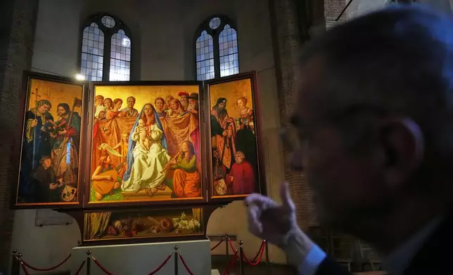 Mons. Peter Klasvogt, the rector of the Teutonic College, talks during an interview with the Associated Press next to a painting exposed in the chapel of the Teutonic College by German artist Michael Triegel, who portrayed as St. Peter Burkhard Scheffler, a homeless man who died from the cold in 2022 on the edge of St. Peter's Square, at the Vatican, Wednesday, Dec. 10, 2025. (AP Photo/Alessandra Tarantino)
