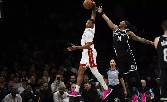 Miami Heat guard Norman Powell, left, grabs a rebound over Brooklyn Nets guard Terance Mann (14) during the first half of an NBA basketball game, Thursday, Dec. 18, 2025, in New York. (AP Photo/Heather Khalifa)
