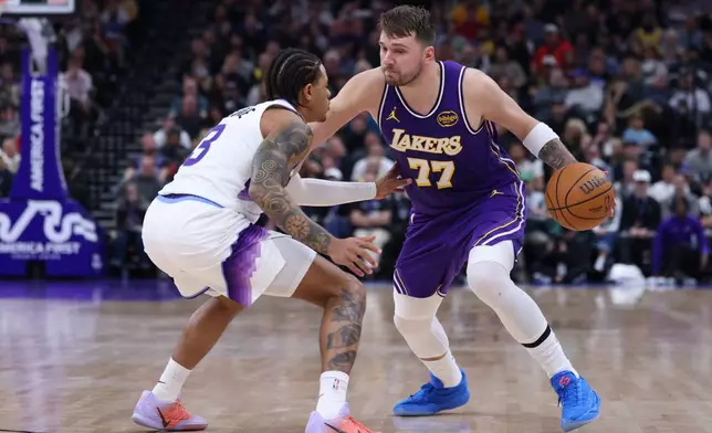 Los Angeles Lakers guard Luka Doncic (77) moves the ball against Utah Jazz guard Keyonte George (3) during the first half of an NBA basketball game Thursday, Dec. 18, 2025, in Salt Lake City. (AP Photo/Rob Gray)