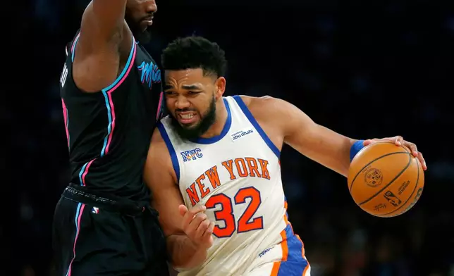 Miami Heat center Bam Adebayo, left, defends against New York Knicks center Karl-Anthony Towns, right, during the first half of an NBA basketball game Sunday, Dec. 21, 2025, in New York. (AP Photo/John Munson)