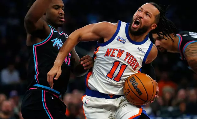 Miami Heat guard Davion Mitchell, left, defends against New York Knicks guard Jalen Brunson (11) during the first half of an NBA basketball game Sunday, Dec. 21, 2025, in New York. (AP Photo/John Munson)