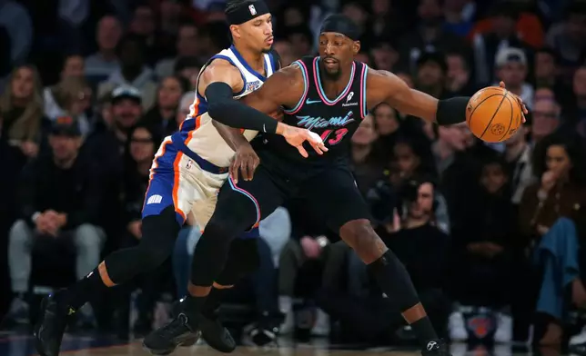 New York Knicks guard Josh Hart, left, defends Miami Heat center Bam Adebayo, right, during the first half of an NBA basketball game Sunday, Dec. 21, 2025, in New York. (AP Photo/John Munson)
