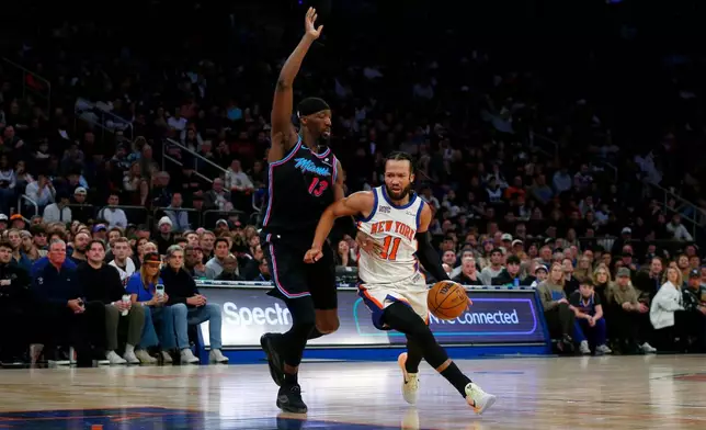 New York Knicks guard Jalen Brunson (11) dribbles around Miami Heat center Bam Adubayo (13) during the first half of an NBA basketball game Sunday, Dec. 21, 2025, in New York. (AP Photo/John Munson)