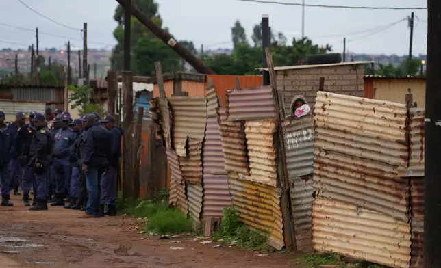South African police gather at the scene of a mass shooting where gunmen killed nine and injured at least 10 in a pub in Bekkersdal, South Africa, Sunday, Dec. 21, 2025. (AP Photo/ Alfonso Nqunjana)