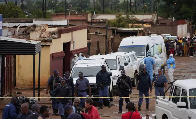 South African police gather at the scene of a mass shooting where gunmen killed nine and injured at least 10 in a pub in Bekkersdal, South Africa, Sunday, Dec. 21, 2025. (AP Photo/ Alfonso Nqunjana)
