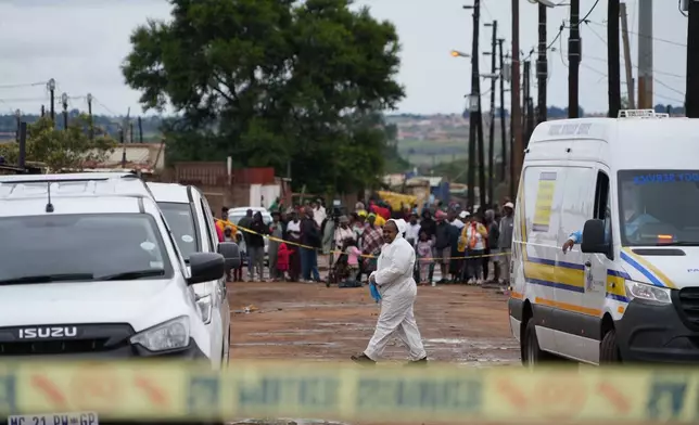 Onlookers gather at the scene of a mass shooting where gunmen killed nine and injured at least 10 in a pub in Bekkersdal, South Africa, Sunday, Dec. 21, 2025. (AP Photo/ Alfonso Nqunjana)