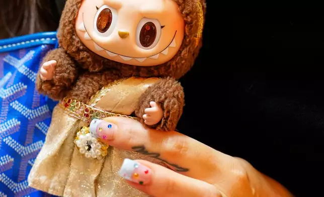 Diep Nguyen shows a Labubu doll to media during the opening of Germany's first shop for Labubu plush dolls in Berlin, Germany, Friday, July 25, 2025. (AP Photo/Markus Schreiber)