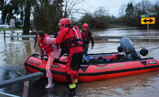 Maery Schine, 11, is helped out of a rescue boat by rescue workers with Chehalis Fire after evacuating with her father Patric, second from left, following flooding after heavy rains in the region Tuesday, Dec. 9, 2025, in Chehalis, Wash. (AP Photo/Lindsey Wasson)