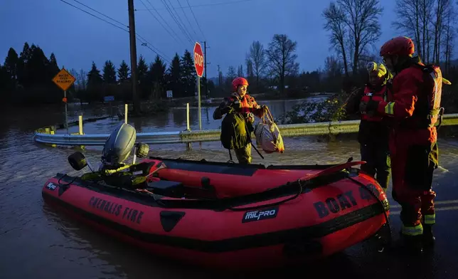 Chehalis Fire rescue workers help residents evacuate their flooded neighborhood after heavy rains in the region Tuesday, Dec. 9, 2025, in Chehalis, Wash. (AP Photo/Lindsey Wasson)
