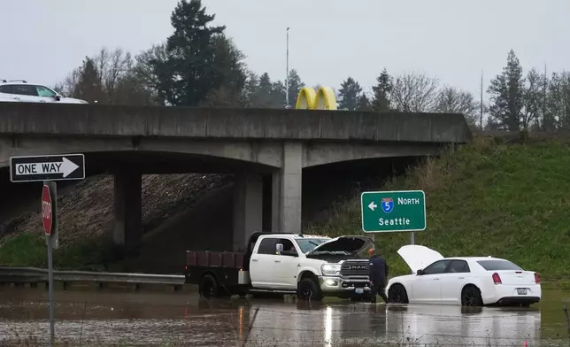 A man checks on a car caught in flooding after heavy rains Tuesday, Dec. 9, 2025, in Napavine, Wash. (AP Photo/Lindsey Wasson)