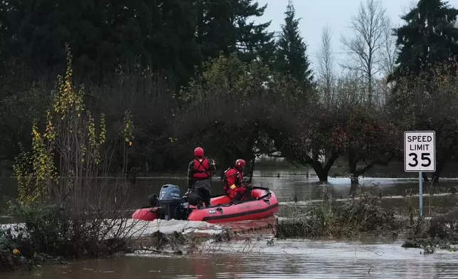 Rescue workers with Chehalis Fire venture into a flooded neighborhood to pick up evacuees after heavy rains, Tuesday, Dec. 9, 2025, in Chehalis, Wash. (AP Photo/Lindsey Wasson)