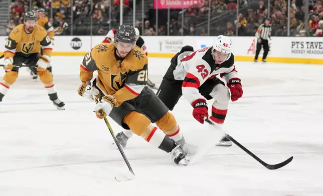 Vegas Golden Knights center Brett Howden (21) skates with the puck against New Jersey Devils defenseman Luke Hughes (43) during the second period of an NHL hockey game Wednesday, Dec. 17, 2025, in Las Vegas. (AP Photo/Candice Ward)