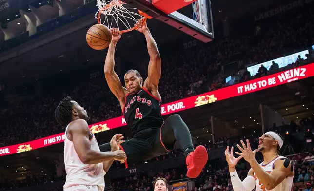 Toronto Raptors' Scottie Barnes (4) dunks as New York Knicks' Josh Hart (3), right, reacts during the first half of an NBA Cup basketball game in Toronto, on Tuesday, Dec. 9, 2025. (Sammy Kogan/The Canadian Press via AP)