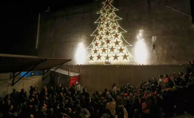 People attend the lighting of a Christmas tree at the Greek Orthodox Mar Elias Church, months after the church was the site of a deadly suicide bombing, in the Dweila neighborhood of Damascus, Syria, Tuesday, Dec. 23, 2025.(AP Photo/Omar Sanadiki)