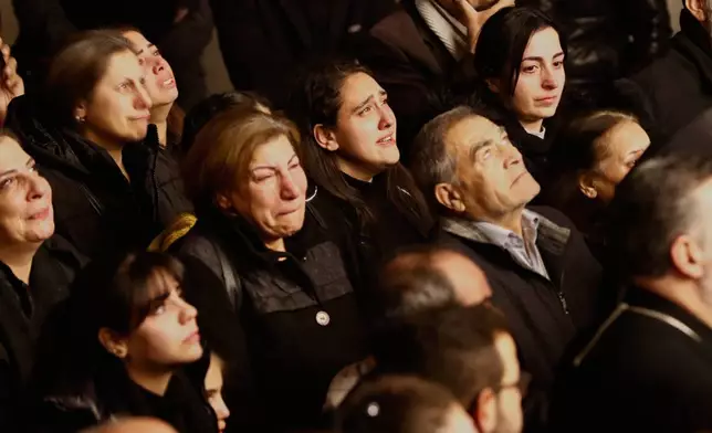 People react as they attend the lighting of a Christmas tree at the Greek Orthodox Mar Elias Church, months after the church was the site of a deadly suicide bombing, in the Dweila neighborhood of Damascus, Syria, Tuesday, Dec. 23, 2025.(AP Photo/Omar Sanadiki)