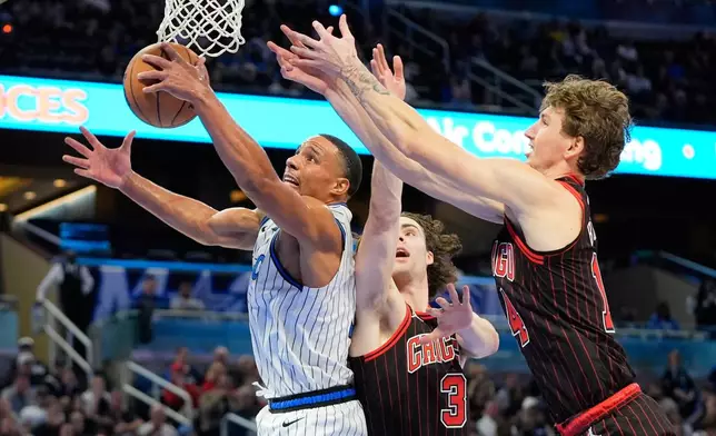Orlando Magic guard Desmond Bane, left, grabs an offensive rebound away from Chicago Bulls guard Josh Giddey (3) and forward Matas Buzelis, right, during the first half of an NBA basketball game, Monday, Dec. 1, 2025, in Orlando, Fla. (AP Photo/John Raoux)