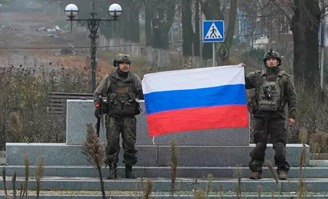 In this image made from video provided by Russian Defense Ministry Press Service on Tuesday, Dec. 2, 2025, Russian soldiers hold a Russian national flag in Pokrovsk, a city in the Donetsk region, Ukraine. (Russian Defense Ministry Press Service via AP)