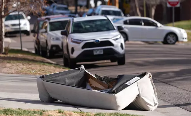 A couch that was blown off the balcony of a high-rise condominium building sits crumpled after falling to the street as hurricane-force winds whipped through the area Thursday, Dec. 18, 2025, in Denver. (AP Photo/David Zalubowski)