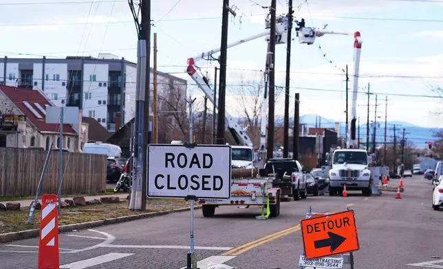 Xcel Energy workers work to repair power lines on a street closed after hurricane-force winds whipped through the metropolitan area and interrupted service to residents, Thursday, Dec. 18, 2025, in Denver. (AP Photo/David Zalubowski)