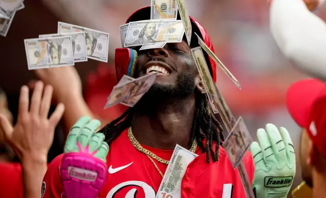 Teammates shower Cincinnati Reds' Elly De La Cruz with play money in the dugout after his two-run homer during the third inning of a baseball game against the Atlanta Braves, in Cincinnati, July 31, 2025. (AP Photo/Carolyn Kaster, File)