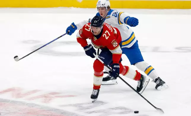 St. Louis Blues right wing Jonatan Berggren (29) chases Florida Panthers center Eetu Luostarinen (27) during the first period of an NHL hockey game, Saturday, Dec. 20, 2025, in Sunrise, Fla. (AP Photo/Rhona Wise)