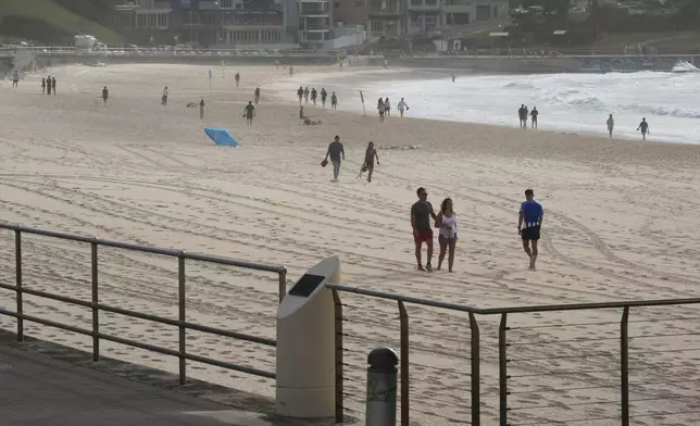 People walk along Sydney's Bondi Beach a day after a mass shooting Monday, Dec. 15, 2025. (AP Photo/Mark Baker)