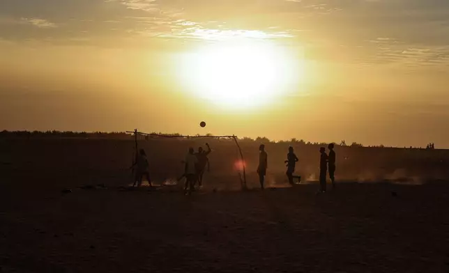 Boys play football as the sun sets in the Mbera Refugee Camp, near Bassikounou, Hodh El Chargui Region, Mauritania, Saturday Nov. 8, 2025. (AP Photo/Caitlin Kelly)
