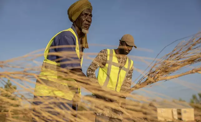 Mbera fire brigade members from the NGO SOS desert demonstrate the brushing technique used to extinguish fires in Mbera Refugee Camp, near Bassikounou, Hodh El Chargui Region, Mauritania, Saturday Nov. 8, 2025. (AP Photo/Caitlin Kelly)