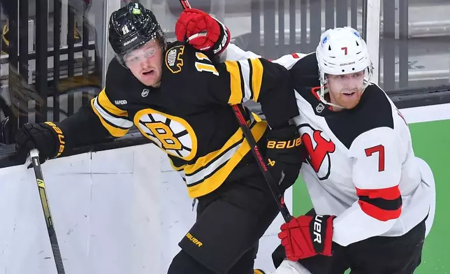Boston Bruins center Casey Mittelstadt (11) and New Jersey Devils defenseman Dougie Hamilton (7) crash into the boards in the first period of an NHL hockey game, Saturday, Dec. 6, 2025, in Boston. (AP Photo/Steven Senne)